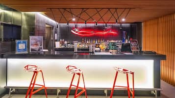 A modern bar area with a counter, bar stools, and a neon light decoration.