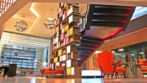A modern interior with a unique bookshelf, bright lighting, and orange chairs. - PARK PLAZA BANGKOK SOI 18 (Bangkok)