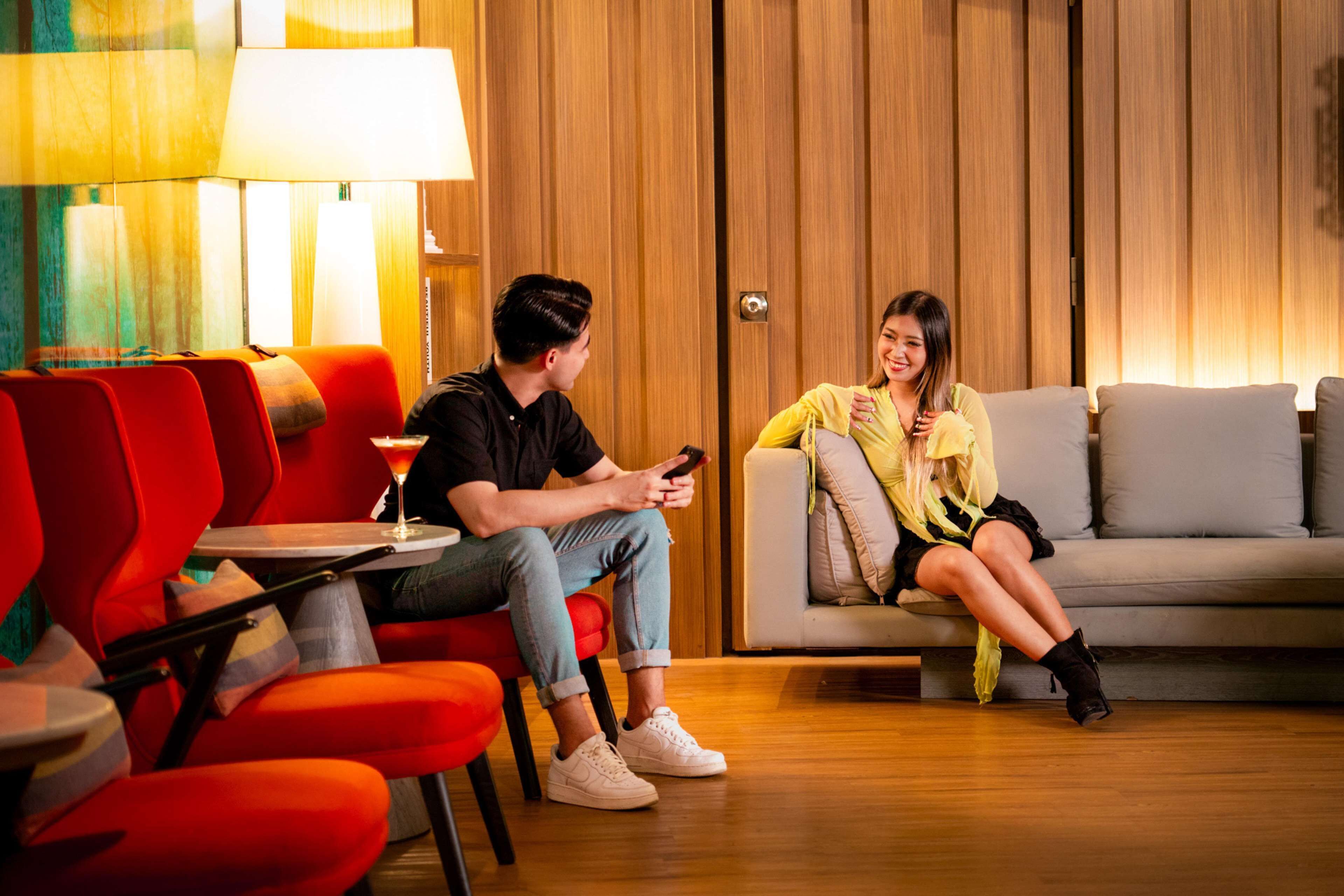 Un salon moderne avec un canapé, des fauteuils rouges et une petite table sur laquelle se trouve une boisson.