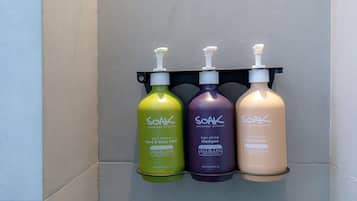 Trois bouteilles de produits de soins de la peau de la marque Soak, posées sur une étagère noire.