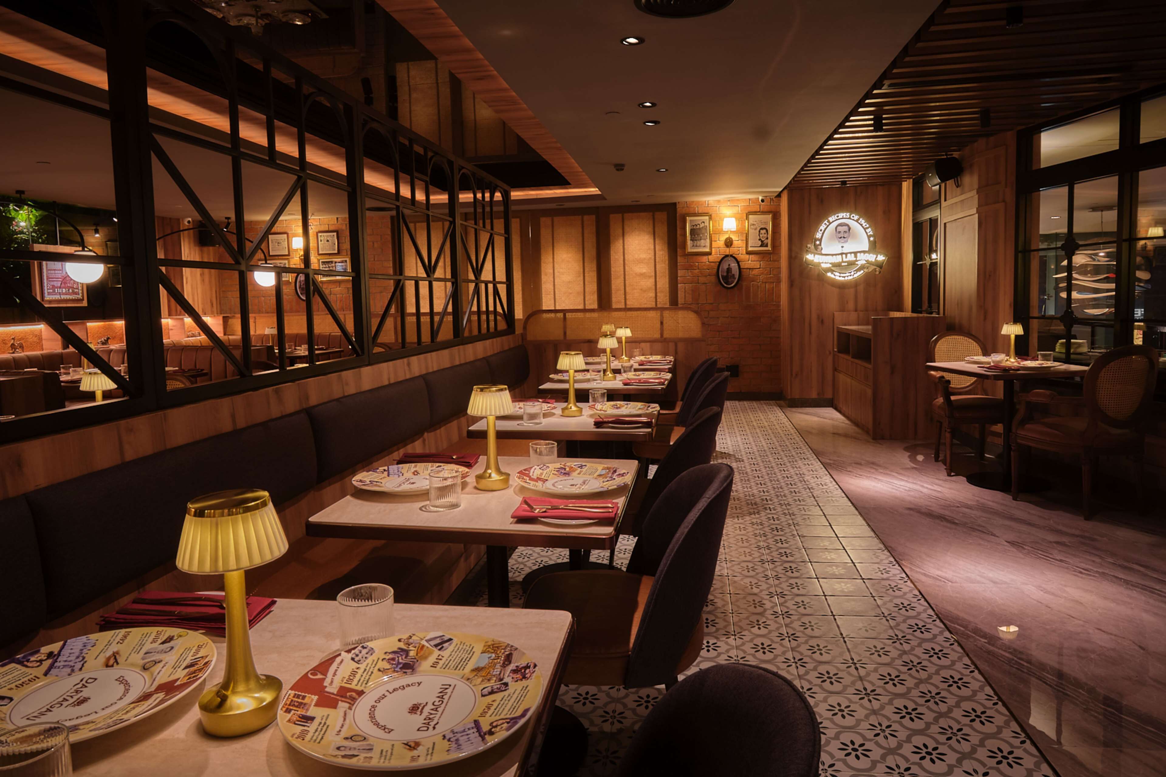 Un restaurante con paneles de madera, mesas dispuestas con platos y lámparas, y un suelo con diseño.