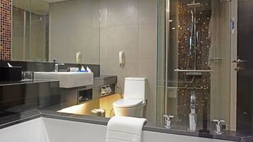 A modern bathroom with a large bathtub, a toilet, and a glass-enclosed shower area.