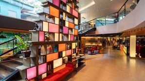 A modern hotel lobby with a high ceiling, a staircase, and a seating area with a red sofa. - PARK PLAZA BANGKOK SOI 18 (Bangkok)
