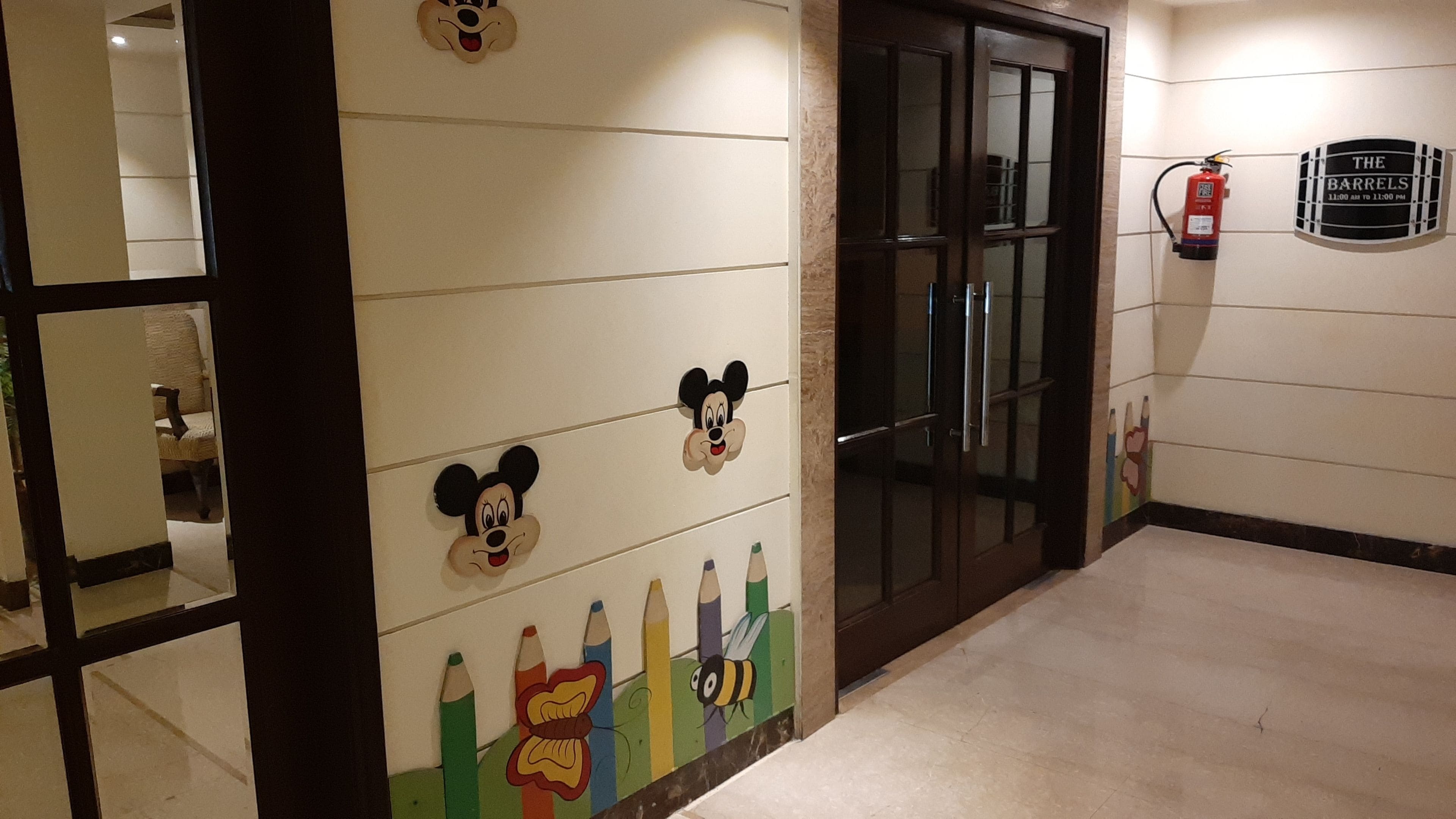 Ein Flur mit Mickey Mouse Dekoration, einem Feuerlöscher und einem Schild mit den Öffnungszeiten der Bar.