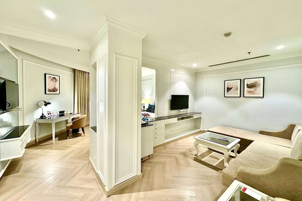 Un salon moderne avec un canapé, une table basse et un téléviseur. Il y a également un coin repas avec une table et des chaises. La pièce est dotée d'un plancher de couleur claire et de murs blancs.