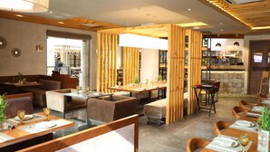 Een modern restaurant met houten scheidingswanden, comfortabele zitplaatsen en netjes opgemaakte tafels met glazen.