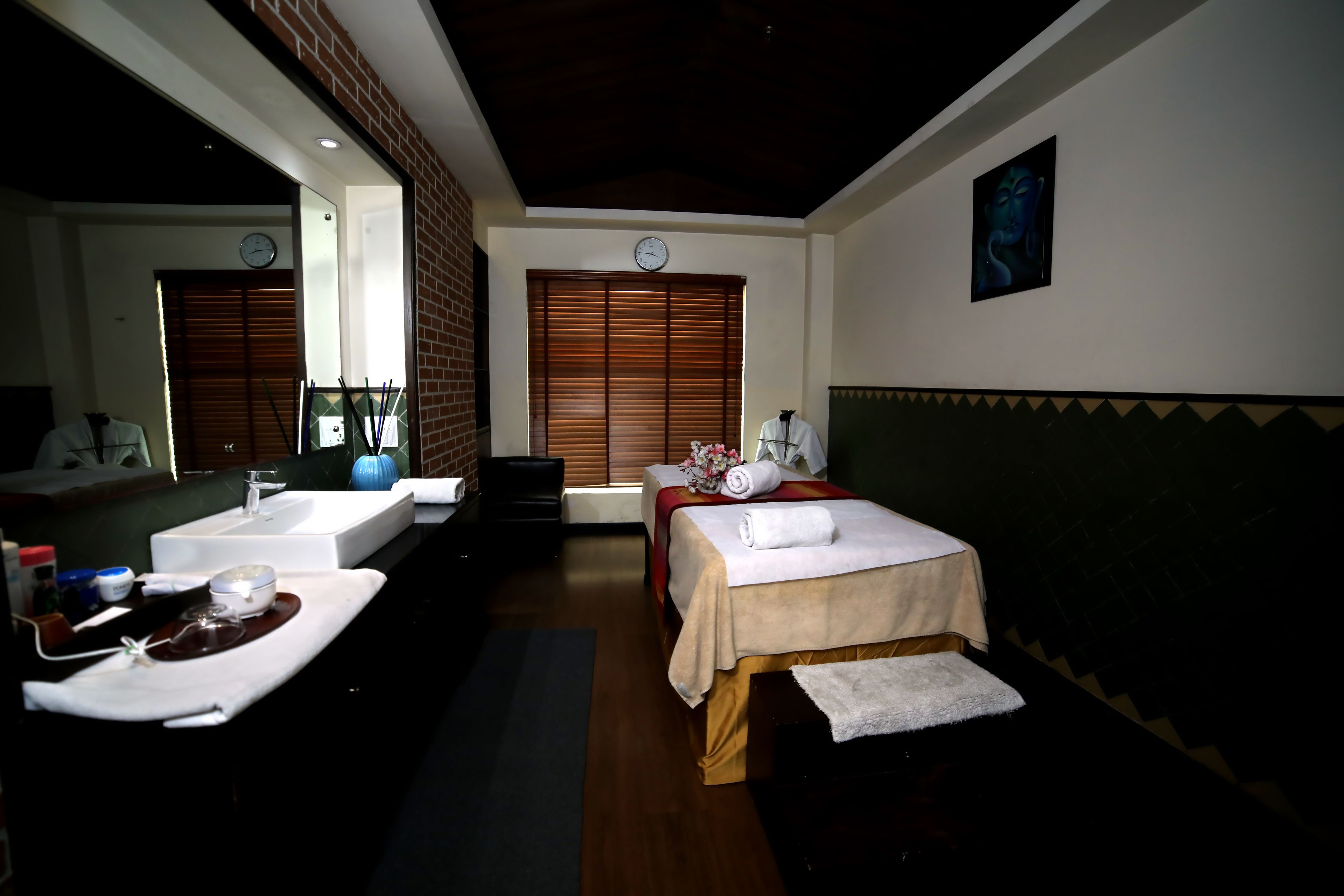 Habitación de hotel con dos camas, un espejo grande, un reloj y una pintura de Buda.