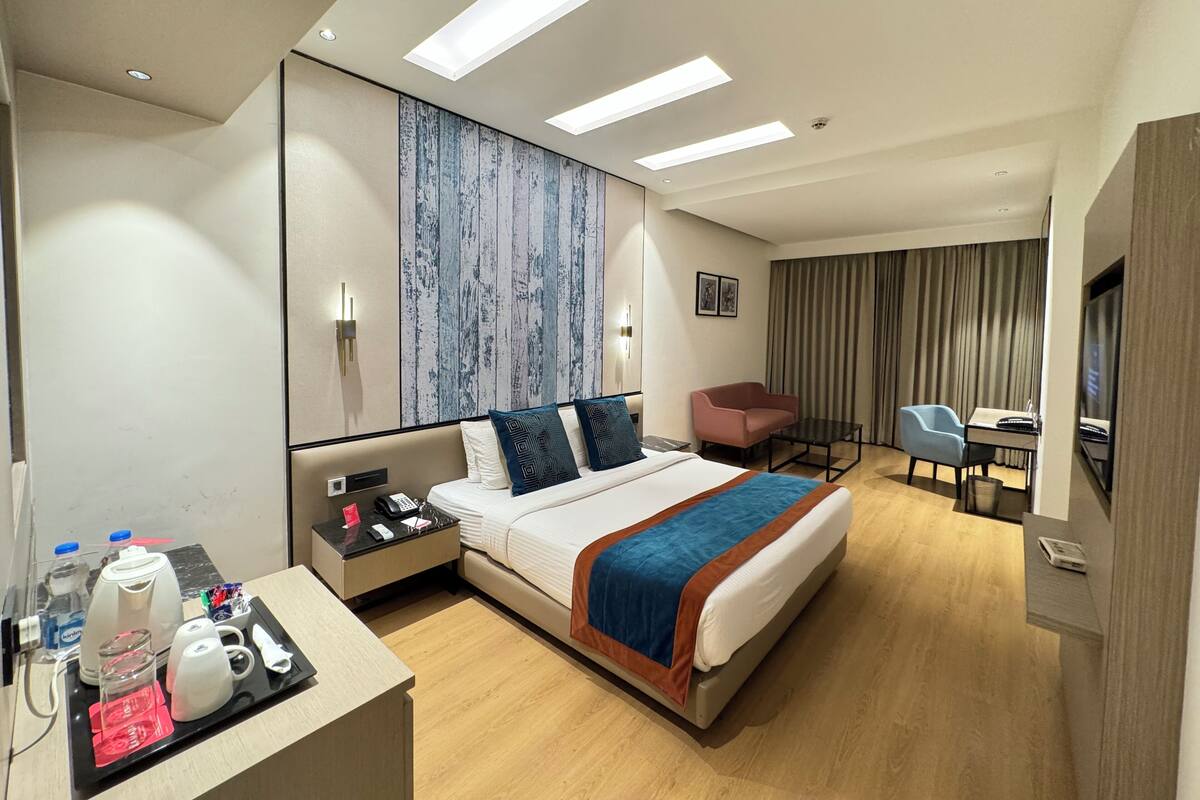 Une chambre d’hôtel comprenant un lit, une table de chevet, un bureau, une chaise et un téléviseur.