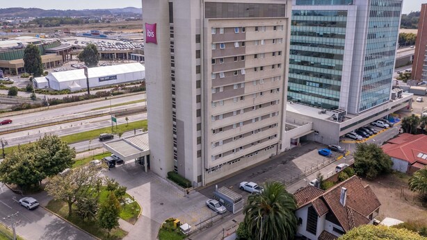 A multi-story hotel with a parking garage and a modern building with reflective windows.