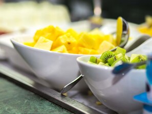 Two white bowls containing diced mango and kiwi on a tray.