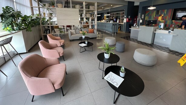 Un vestíbulo moderno con zonas de estar, una recepción y un bar.
