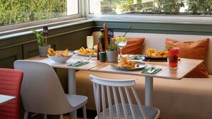 Un comedor con una mesa preparada para dos, un sofá y un ventanal con vistas al verdor.