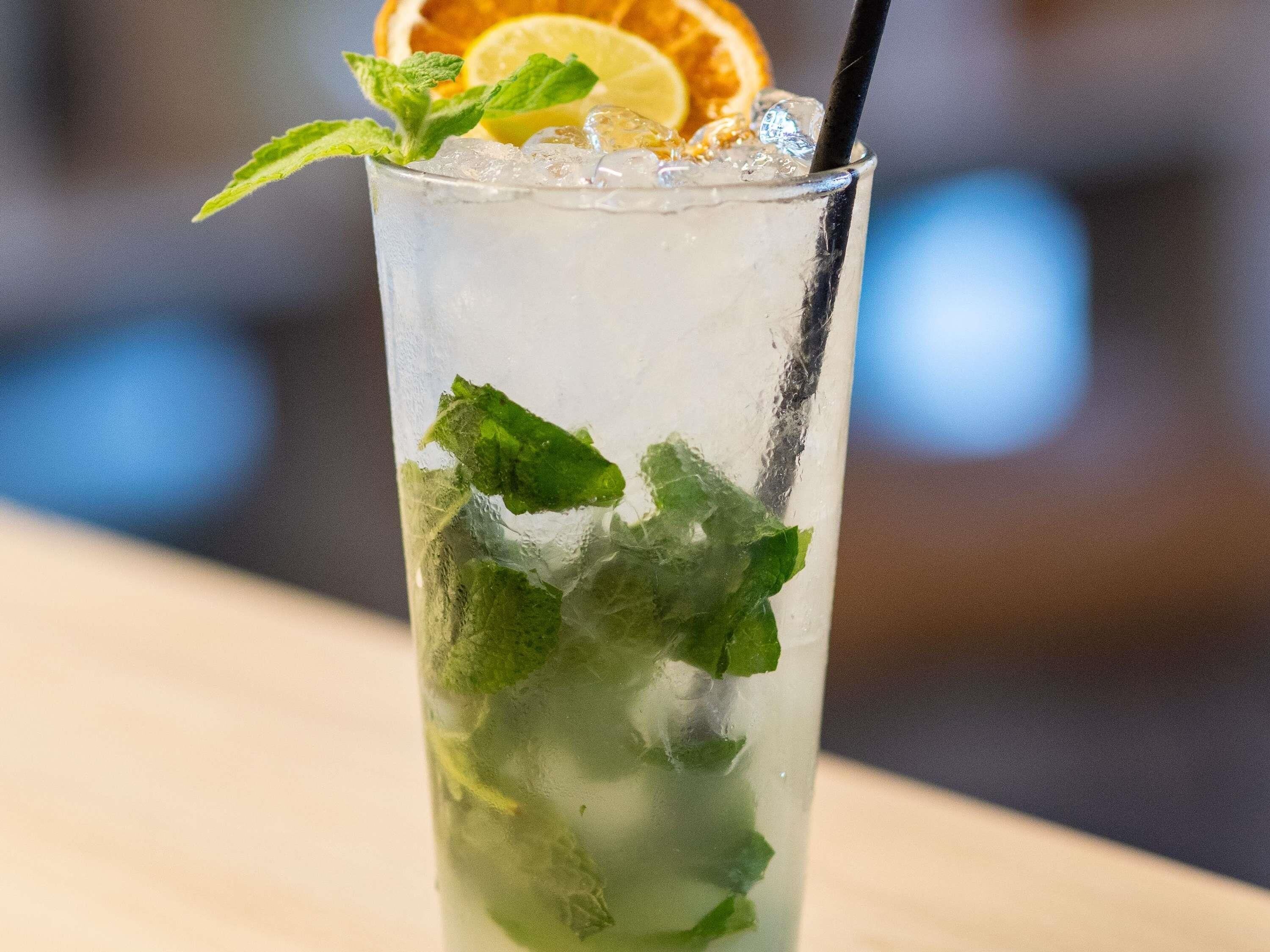A tall glass with ice, mint leaves, and a slice of orange.