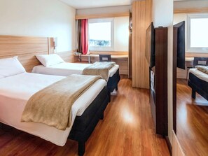 A hotel room with two beds, a desk, a chair, a TV, and a window with a view.