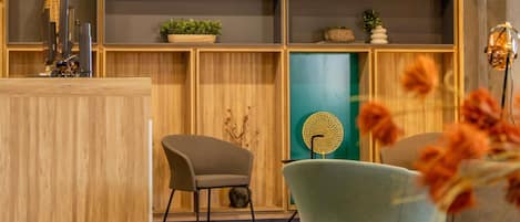 Un espace d’accueil avec un lambris en bois, deux fauteuils rembourrés, un mur d’accent bleu et un élément décoratif mural.