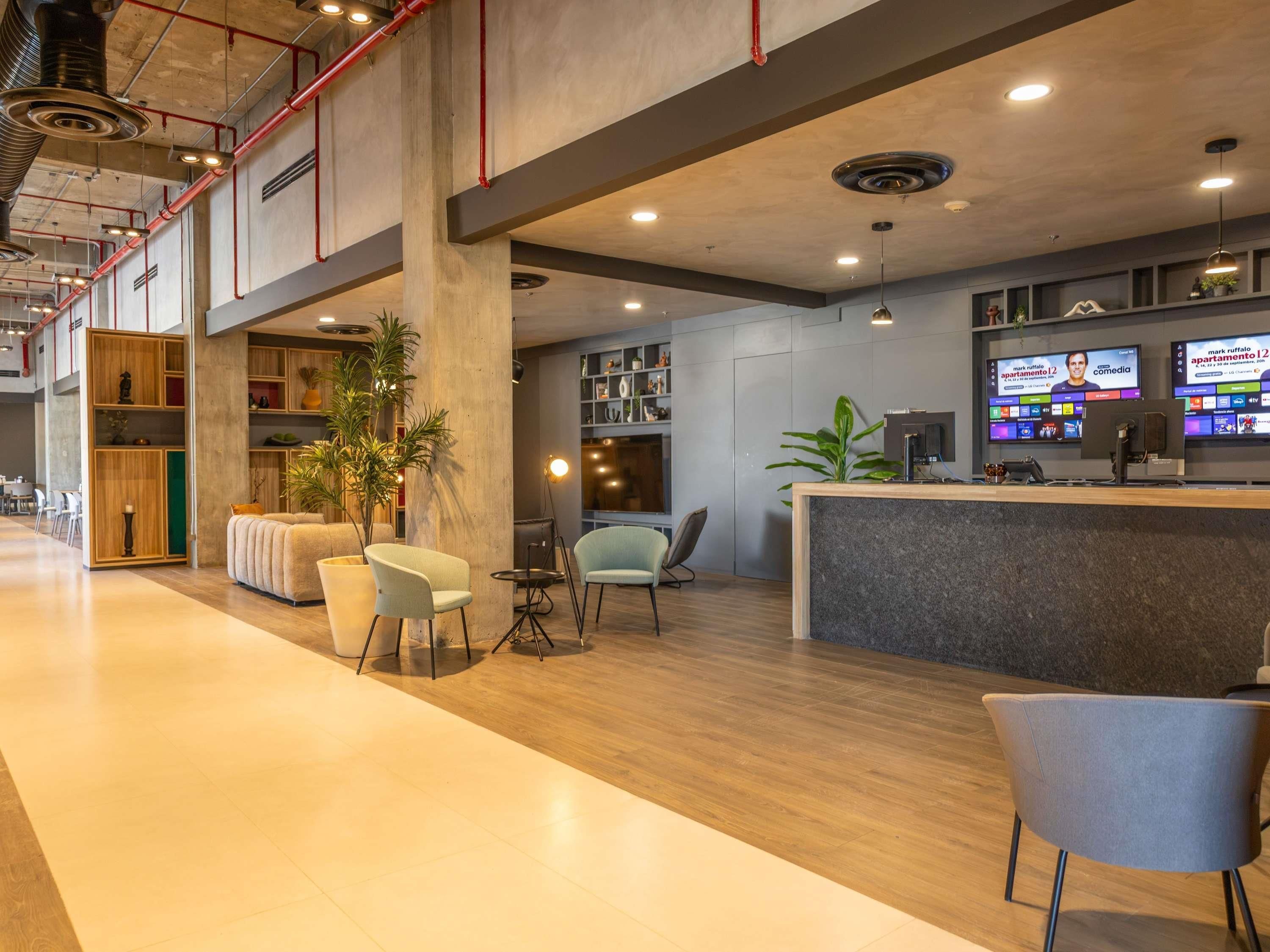 A spacious lobby with a reception desk, seating area, and a large plant.