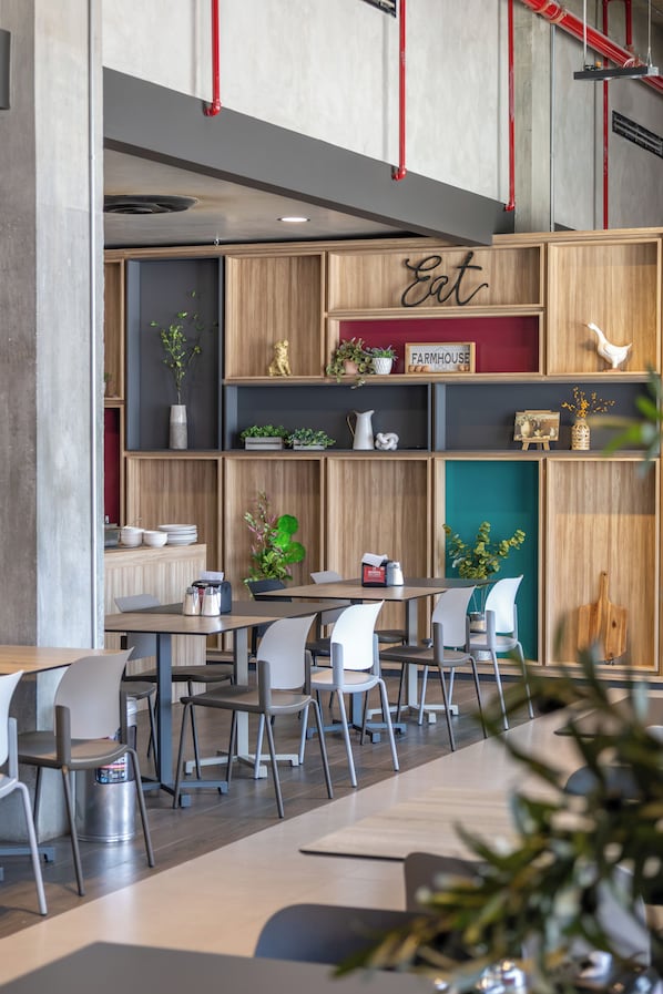A modern dining area with wooden shelves, a sign that reads 'Eat,' and a variety of decorative items.