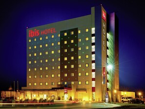 A multi-story hotel with a prominent 'ibis HOTEL' sign, a large entrance, and a parking area. - ibis Juarez Consulado (Ciudad Juárez)