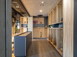 A modern kitchen with wooden cabinetry, a central island, and built-in shelves.