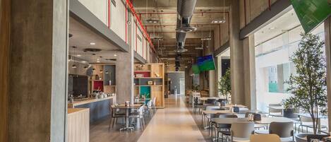 A spacious indoor area with a long counter, multiple tables, and chairs arranged for dining.