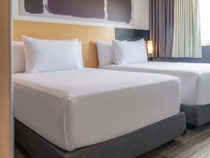 Two twin beds with white linens in a hotel room.