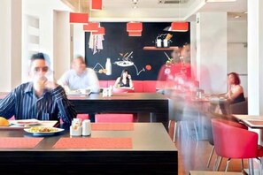 A modern dining area with red chairs and tables, a blackboard with drawings, and a casual atmosphere. - ibis Juarez Consulado (Ciudad Juárez)