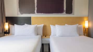 Habitación de hotel con dos camas, una mesita de noche y una obra de arte colgada en la pared.