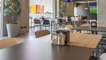 A modern dining area with tables, chairs, and a coffee machine.
