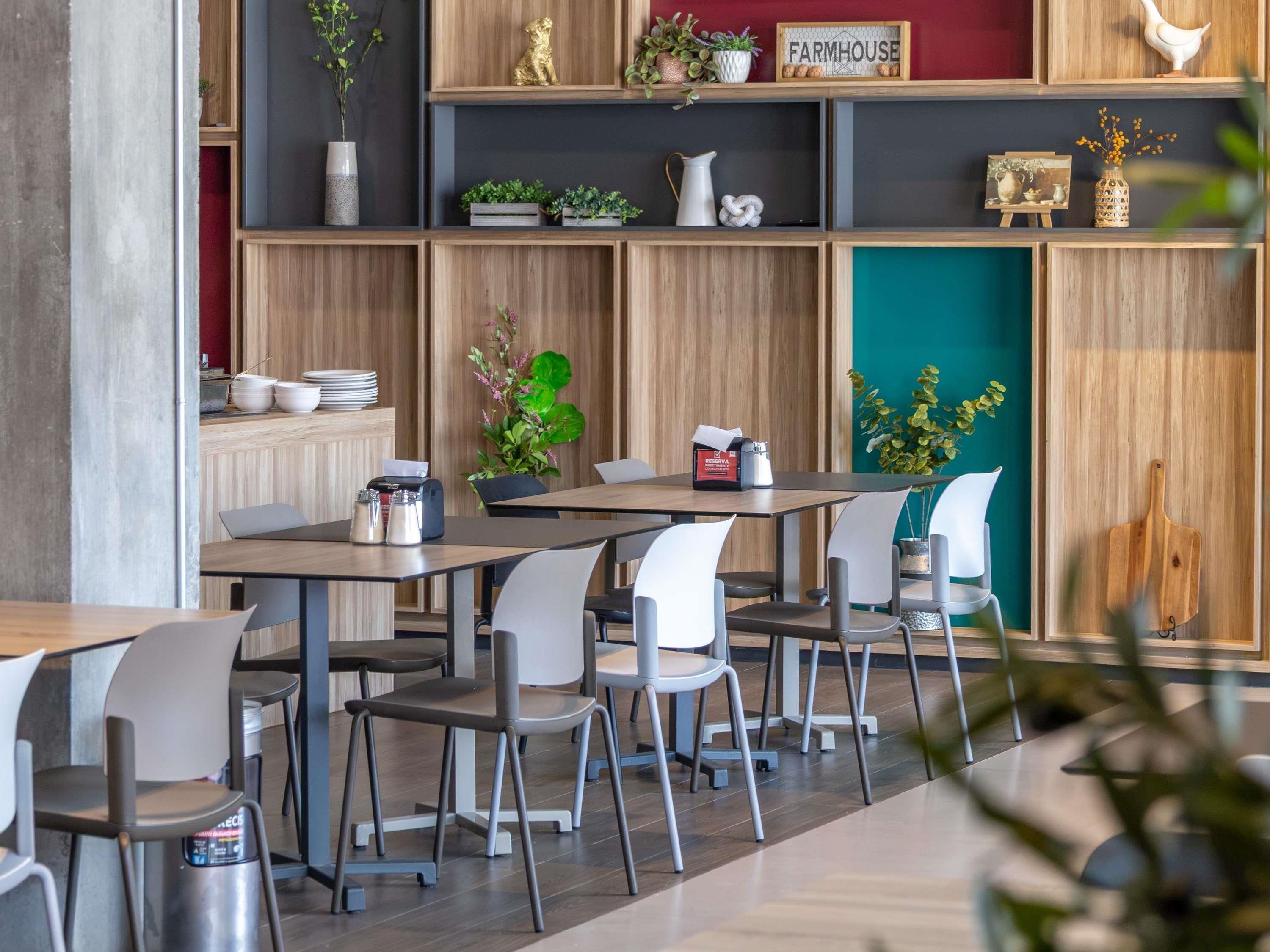 Un intérieur de restaurant moderne avec des lambris en bois, des chaises blanches et une variété de plantes.