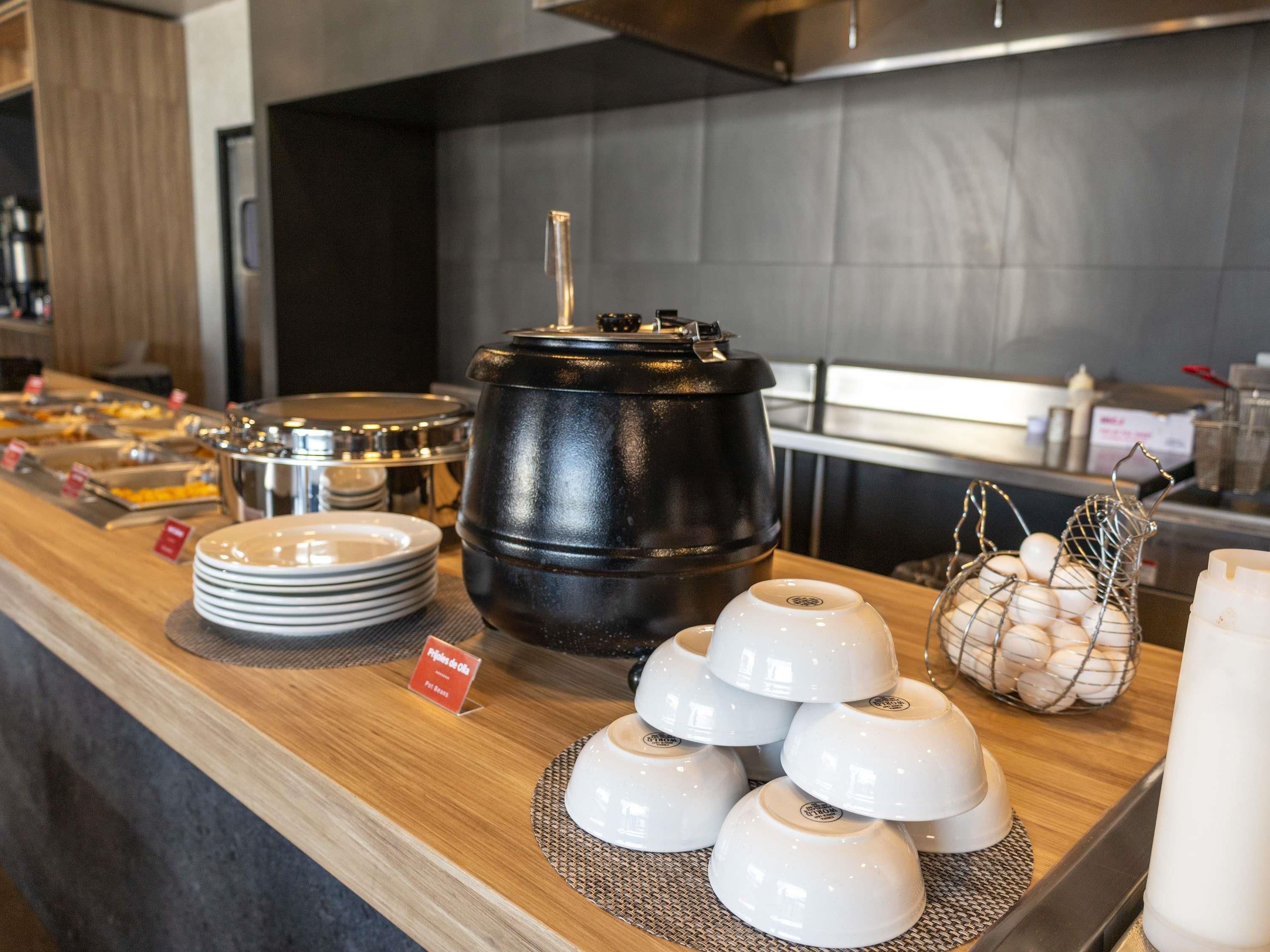 A buffet setup with various food containers, plates, and a sign indicating the type of food available.