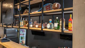 Zona de bar con estantes mostrando balones deportivos, botellas y un cartel que dice 'Baseball'.
