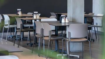 A modern dining area with tables and chairs, some with condiments on them.