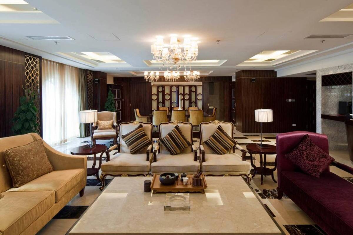 Un vestíbulo espacioso con un área de estar central que incluye sofás y sillones, una araña y una mesa de centro con una bandeja.