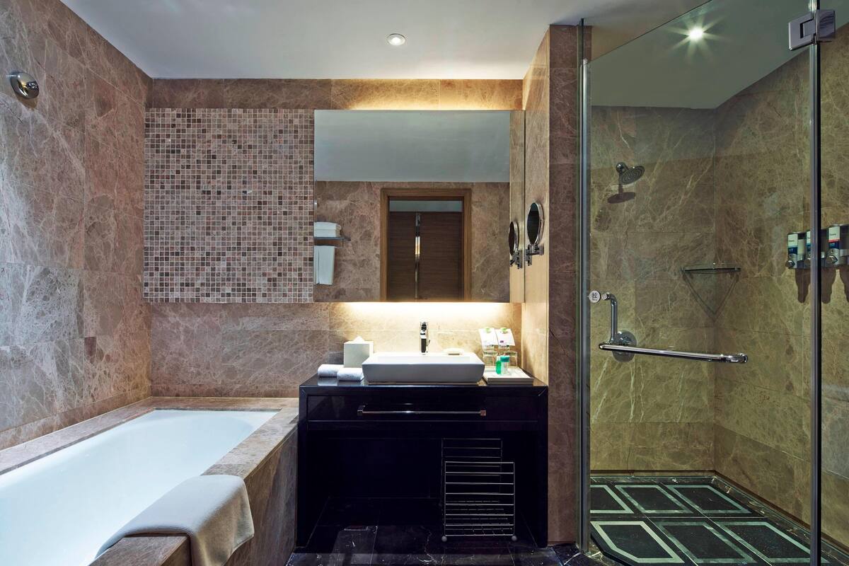 Un baño moderno con bañera, tocador con lavamanos, espejo y zona de ducha.