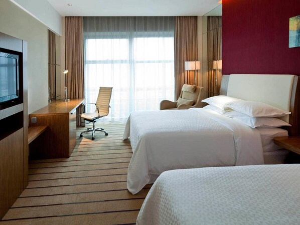 A hotel room with two beds, a desk, a chair, a TV, and large windows. - Four Points by Sheraton Qingdao Chengyang (Qingdao)