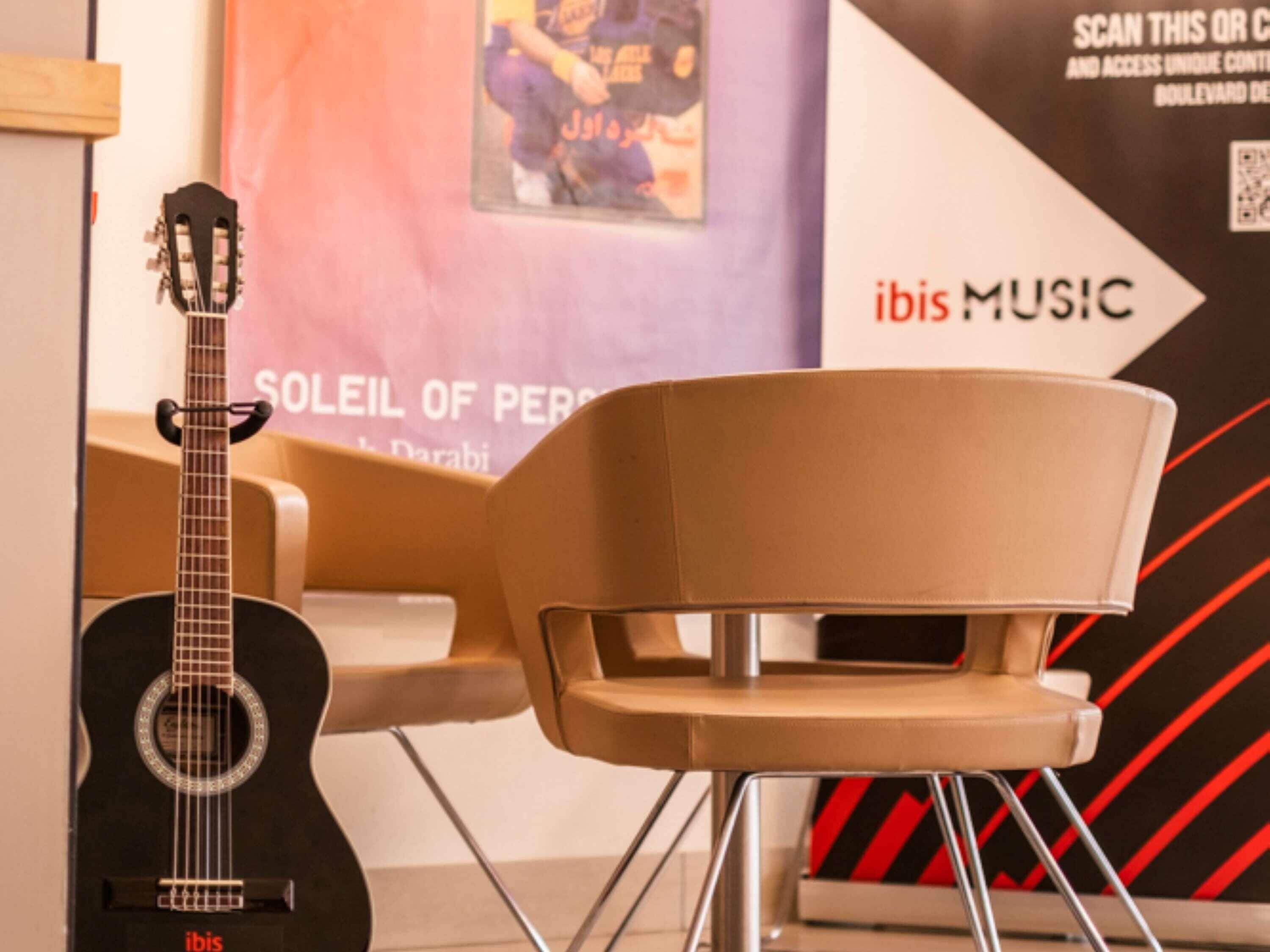 Una guitarra, una silla y una pared con texto y un código QR.