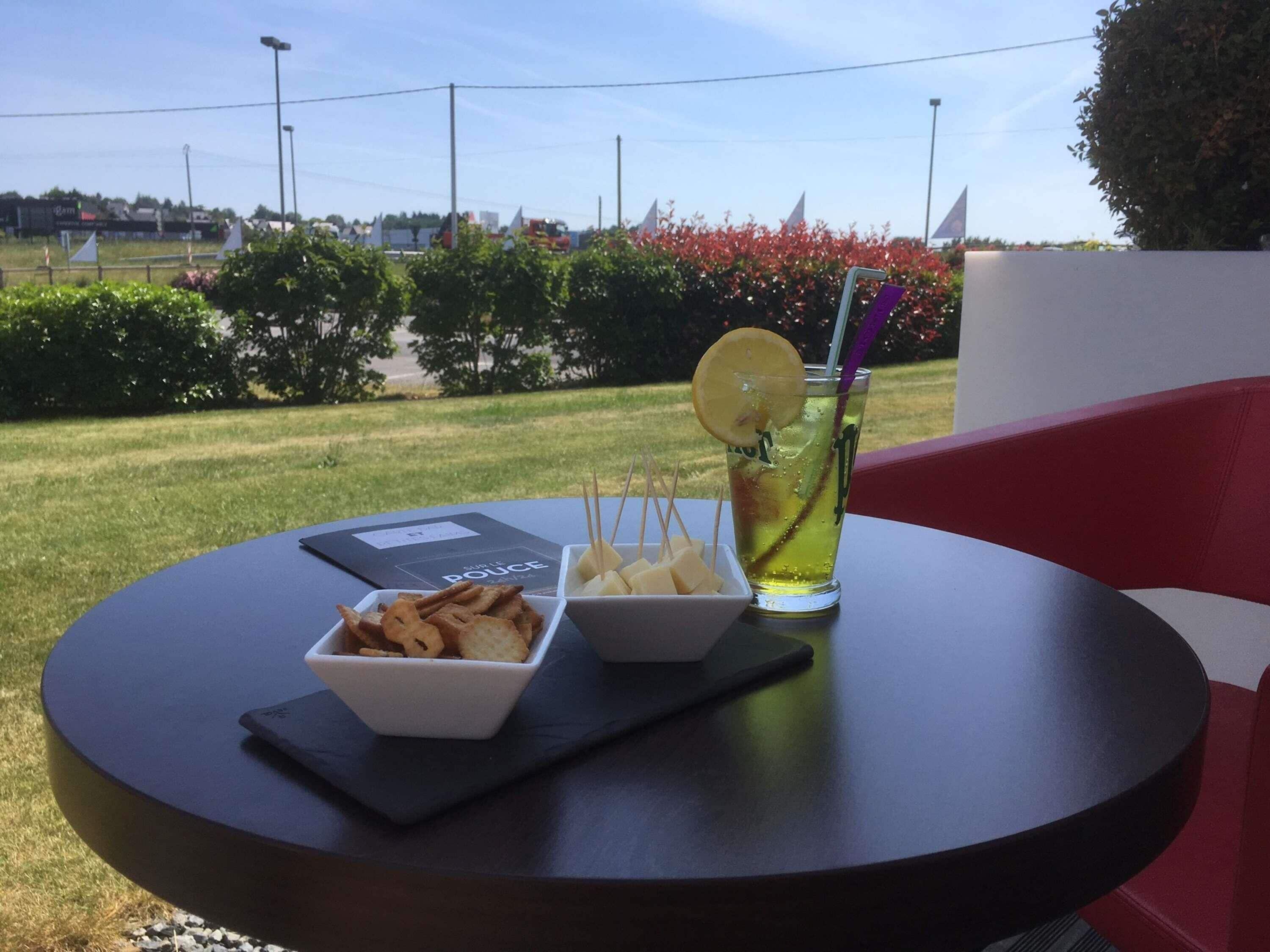A table with a drink, a bowl of snacks, and a menu.