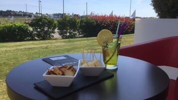 A table with a drink, a bowl of snacks, and a menu.