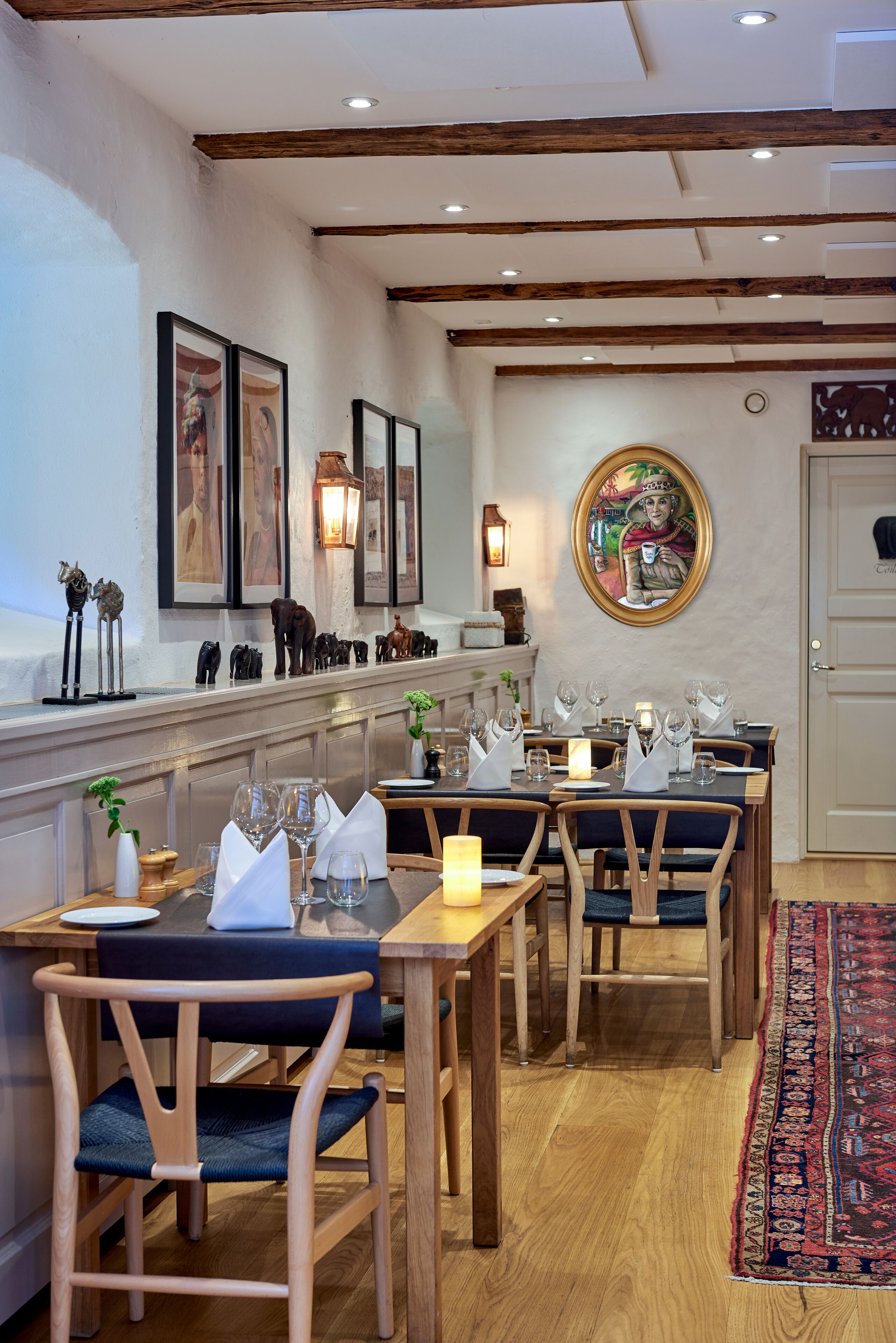 Un restaurant amb taules i cadires de fusta, i una catifes decorativa.