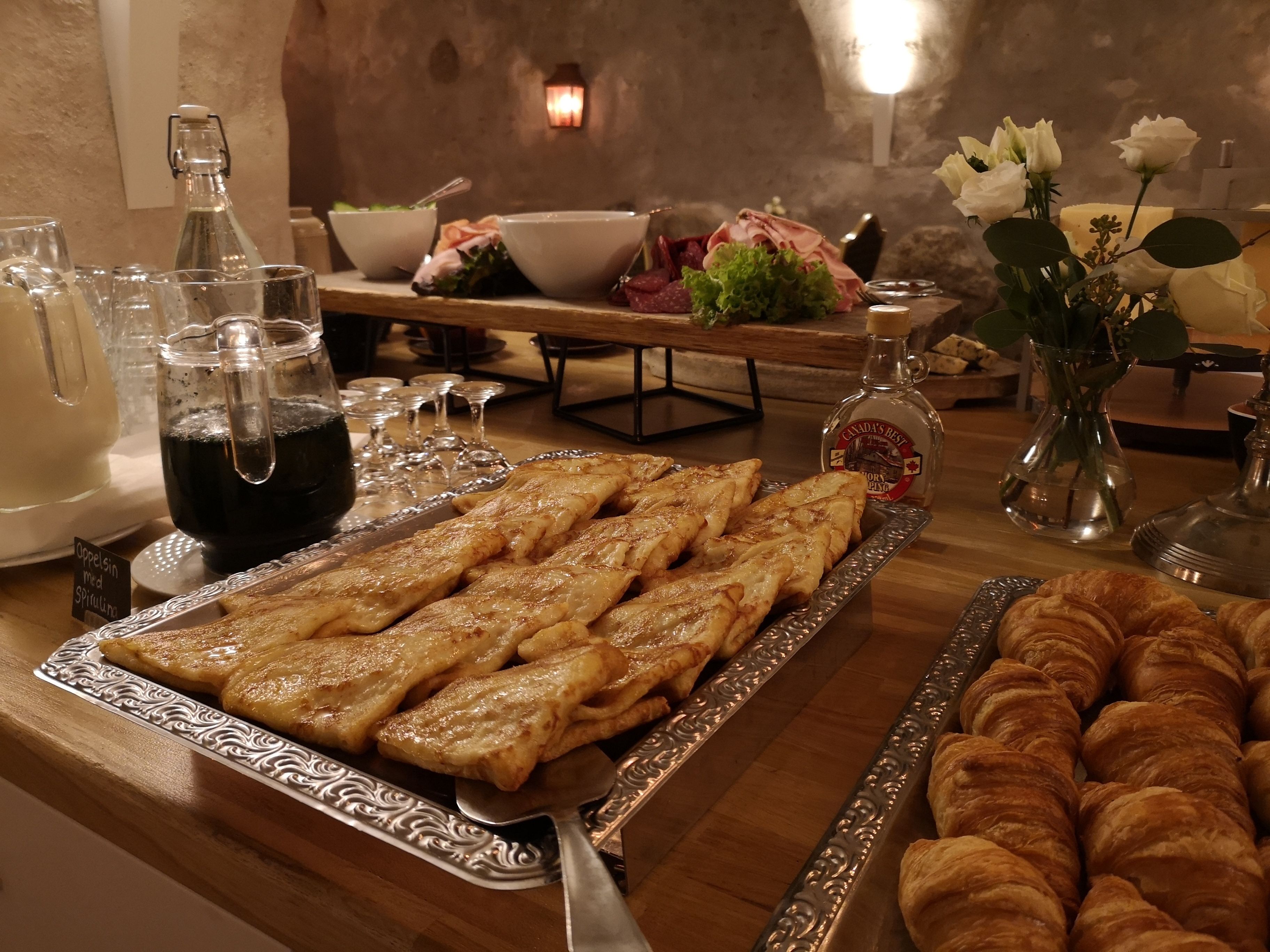 Un bufé de desayuno con pasteles, una botella de Canada’s Best y un florero con flores.