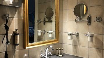 A bathroom with a large mirror, a sink, and a towel rack.