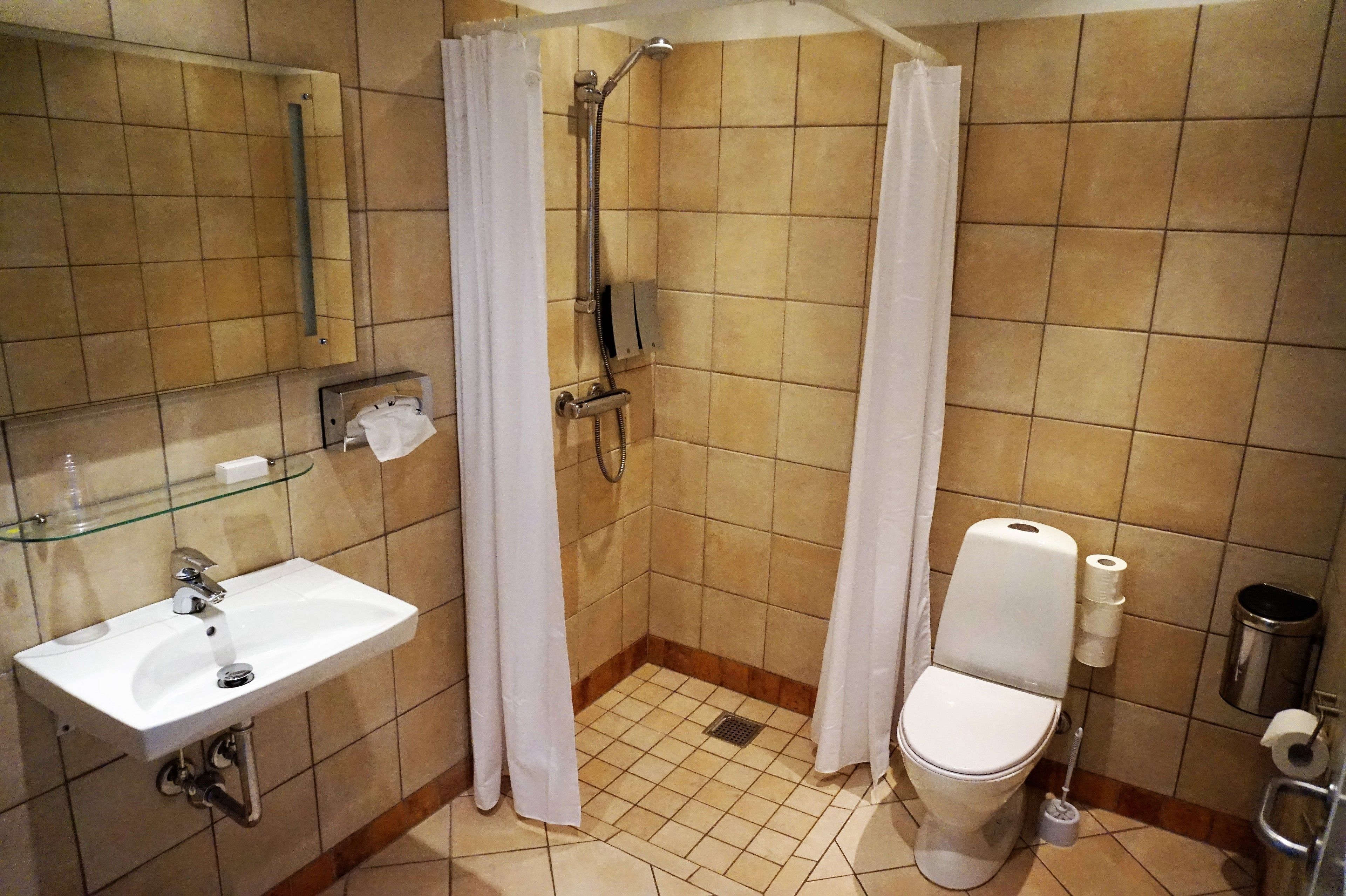 A small bathroom with a shower, toilet, and sink.
