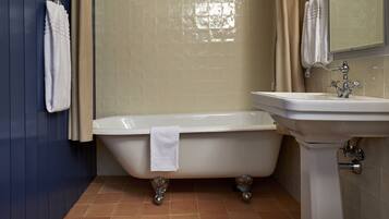 A bathroom with a freestanding bathtub, a sink, and a mirror.
