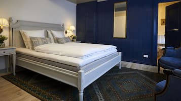 Un dormitorio con cama, mesitas de noche, espejo y una silla.