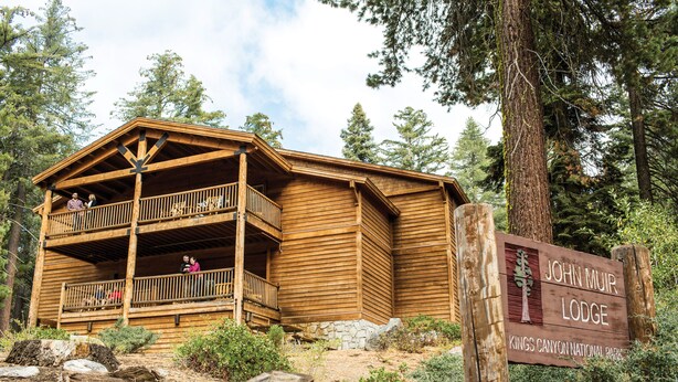 Una cabaña de madera con balcón, rodeada de árboles y un letrero que indica que es el John Muir Lodge en el Parque Nacional Kings Canyon.