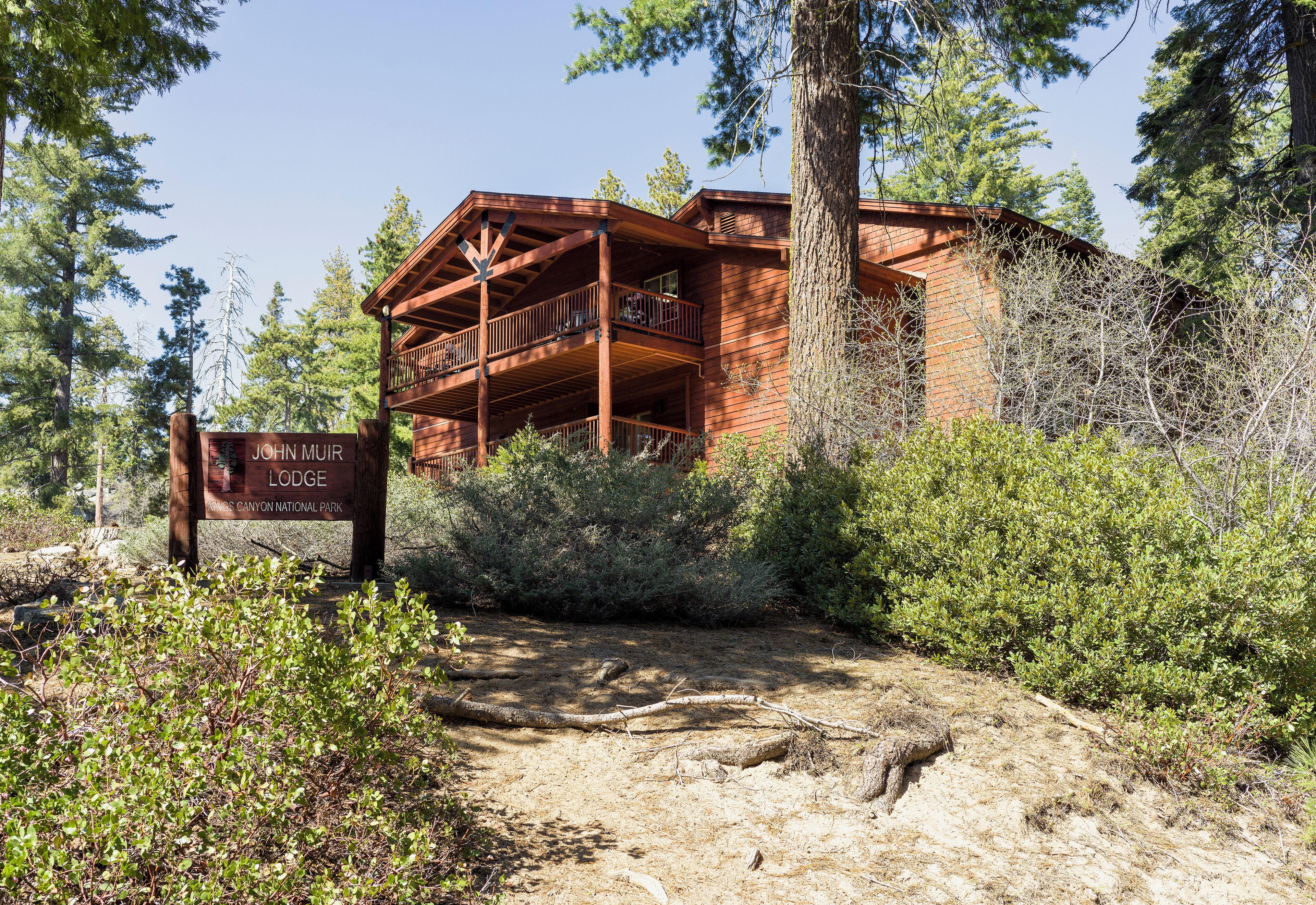 A lodge with a wooden exterior, a balcony, and a sign indicating its name and location.