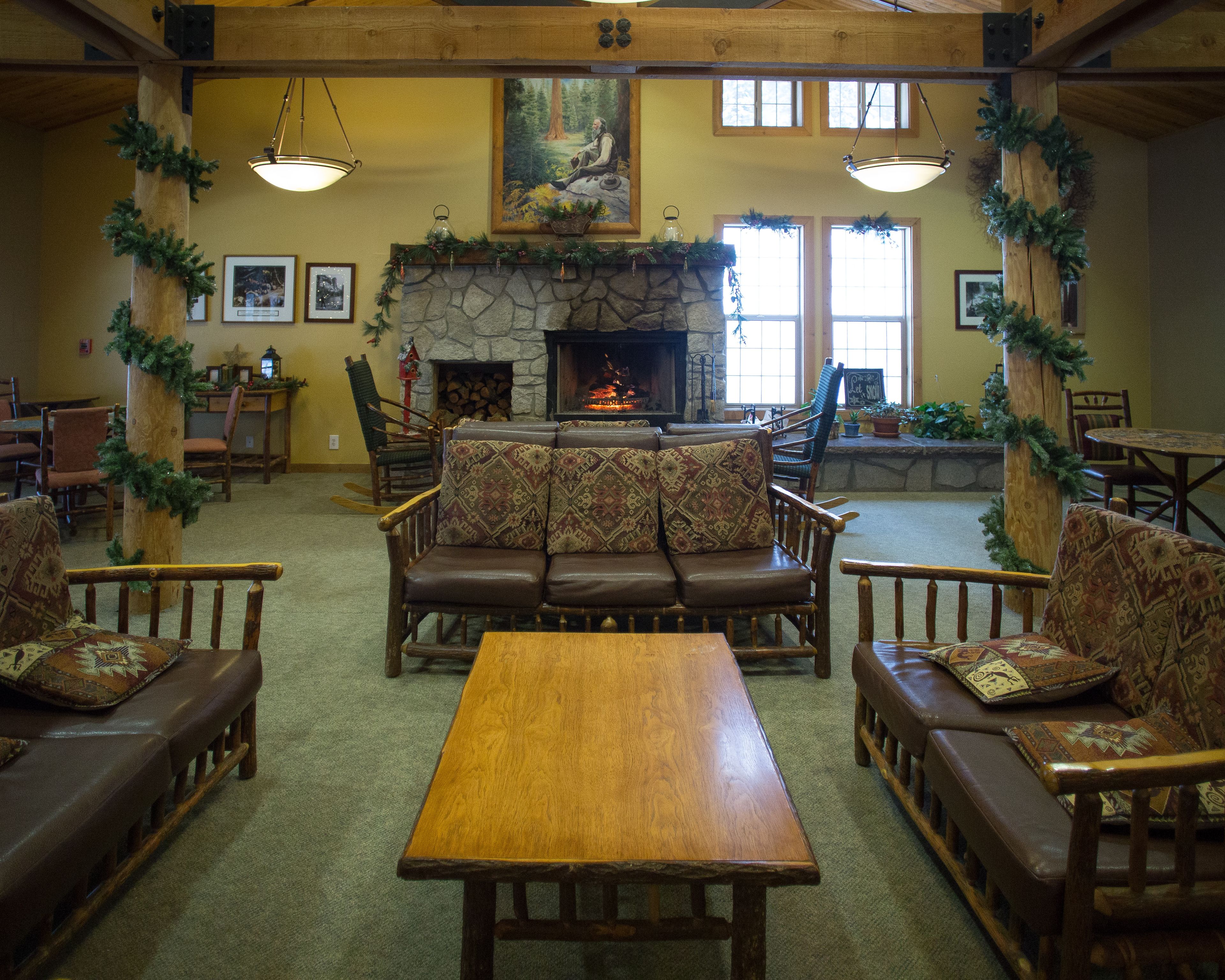 Un intérieur chaleureux de chalet avec une cheminée en pierre, des meubles en bois et des décorations festives.