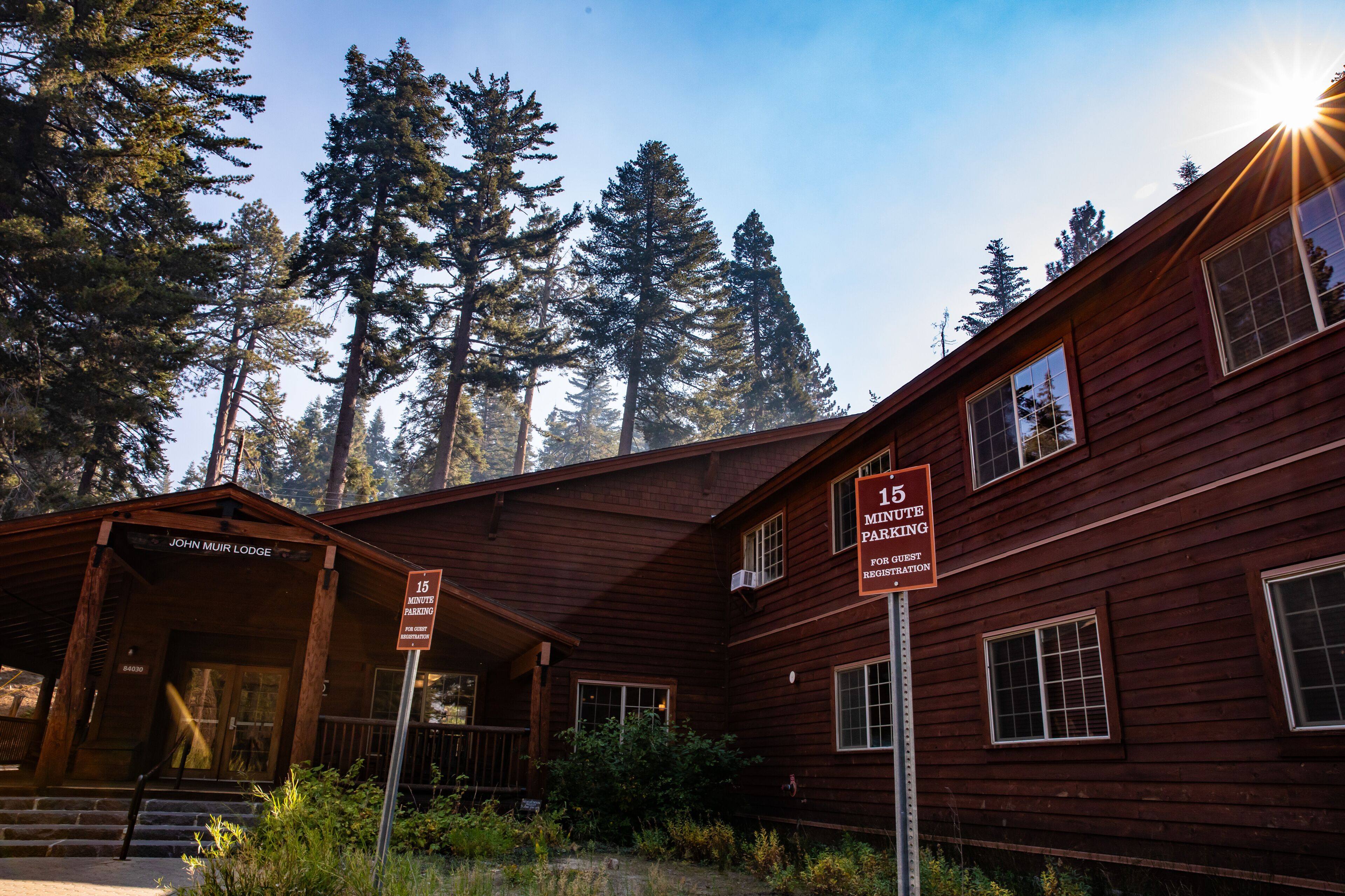 A rustic wooden lodge with a porch and a sign indicating 15-minute parking for guests.