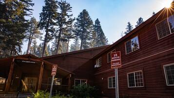 A rustic wooden lodge with a porch and a sign indicating 15-minute parking for guests.