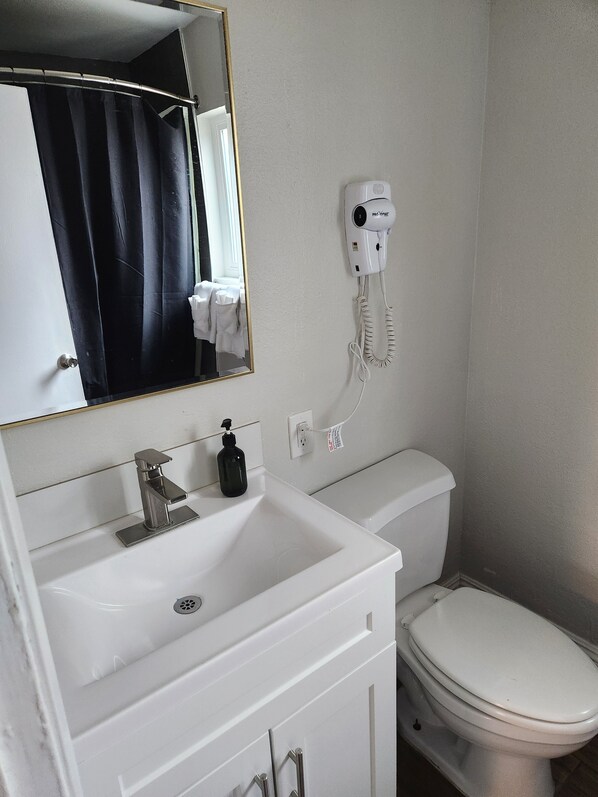 A bathroom with a white sink, a mirror, a hairdryer, and a toilet.
